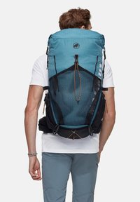 Blå och svart ryggsäck med meshnät på baksidan, justerbara axelremmar och en övre dragsko. Texturerad tyg med en logotypdetalj.