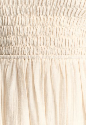 Lichtbeige jurk met geplooide ruches aan het lijfje en een losse, vloeiende rok. Gemaakt van zacht, gestructureerd materiaal.