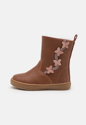 Botte pour enfant marron avec semelle plate, décorée d'une bande scintillante et de quatre appliques papillons roses sur le côté extérieur.