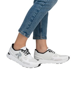 Scarpe da ginnastica bianche con accenti neri, parte superiore in rete e lacci. Suola testurizzata con un design imbottito, abbinate a jeans in denim a cropped.