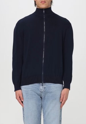 Maglione blu navy con zip, colletto alto, texture a coste e maniche lunghe. Presenta una zip a tutta lunghezza e un girovita aderente.