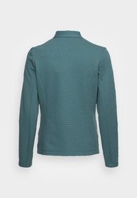 Chaqueta de manga larga color azul verdoso con una superficie texturada y un cuello, con hombros ajustados y una parte trasera recta. Diseño liso sin acentos.