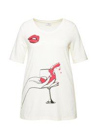 Vit t-shirt med kort ärm som har en grafisk design av röda läppar och en hand som håller ett glas med vätska som stänker, tillverkad av mjuk tyg.