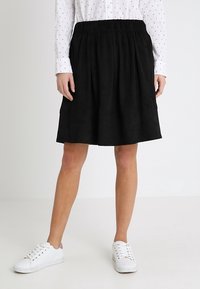 Hame hitam sepanjang lutut terbuat dari kain lembut dengan pinggang elastis. Dipadukan dengan kemeja putih lengan panjang dan sepatu kets putih.