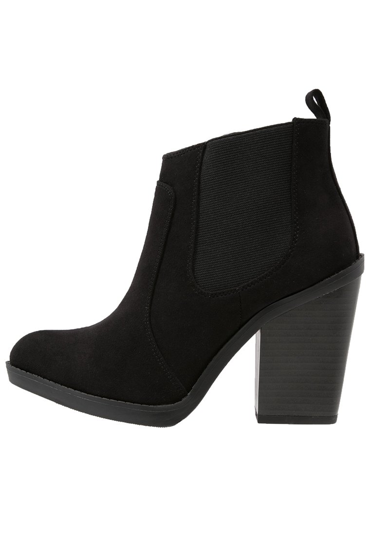 Bottine en daim noir avec panneaux latéraux élastiques, bout arrondi et talon bloc texturé. Dotée d'une languette à l'arrière pour un enfilage facile.