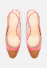 Roze suede espadrile s remenima na petu i kapom od smeđeg kože. Unutrašnjost je glatka, s zaobljenim oblikom.