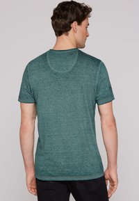 Camiseta de manga corta a rayas verdes con un cuello redondo, hecha de tela suave, con costuras sutiles y un corte relajado.
