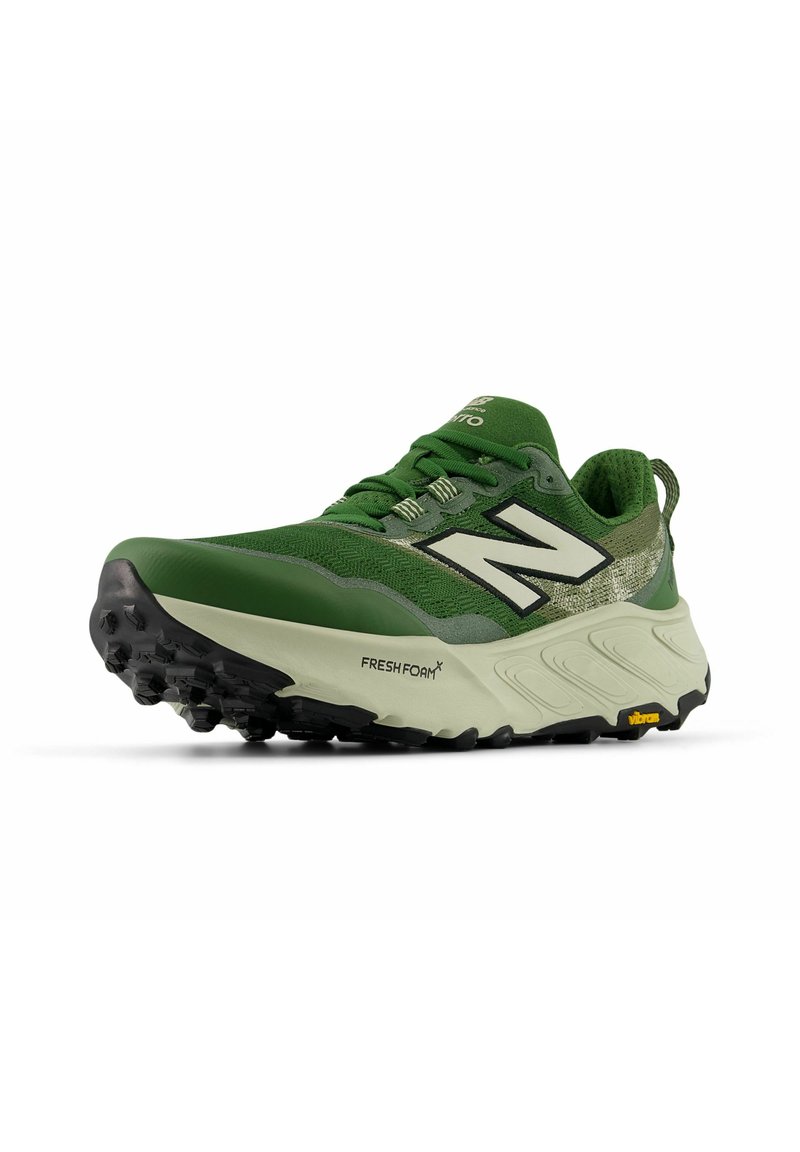 Grüne und beige New Balance Laufschuhe mit strukturierten Sohlen, Schnürsenkeln, großem "N"-Logo und sichtbarer Fresh Foam Dämpfung im Zwischensohle.