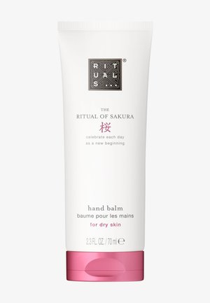 Tubka balsamu do rąk „The Ritual of Sakura“ do skóry suchej, biała z różową nakrętką, 70 ml, tekst po angielsku i francusku.