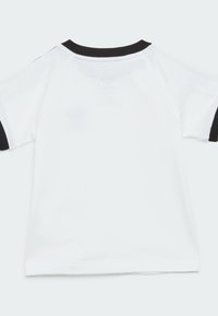 T-shirt bianco a maniche corte con colletto nero a coste e dettagli sulle maniche, caratterizzato da una texture di tessuto semplice e liscia.