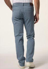 Jeans de mezclilla azul claro con un corte recto, que cuentan con un parche de cuero marrón en la cintura, dos bolsillos traseros y una textura suave.