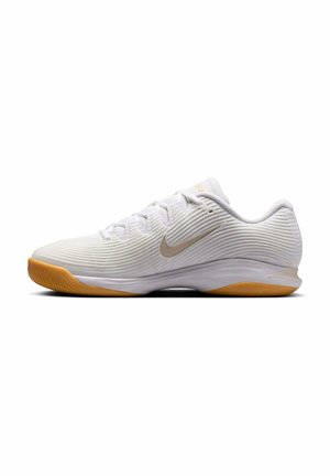 Witte lage sportschoen met gestructureerd patroon, lichtbruine Nike Swoosh, witte veters en een rubberen zool.