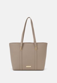 Beige tote taske lavet af tekstureret materiale med to skulderremme. Har guldfarvet hardware og en plade på fronten.