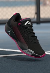Schwarzer Sportschuh mit strukturiertem Design, pinken Akzenten, Schnürverschluss und einem silbernen "Zoom"-Label an der Seite, das ein Jumpman-Logo enthält.