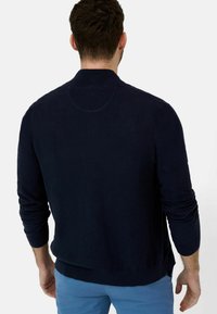 Dunkelblauer Strickpullover mit rundem Kragen und gerippten Bündchen. Verfügt über eine glatte Textur und ein tailliertes Design mit geradem Saum.