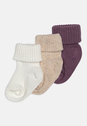 Trois paires de chaussettes tricotées avec des bords côtelés en blanc, beige et violet foncé. La texture semble douce et extensible.