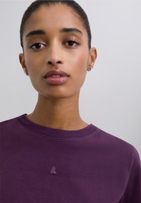 Paarse katoenen T-shirt met een ronde hals en een klein geborduurd logo op de borst. Gladde textuur en een ontwerp met een relaxte pasvorm.