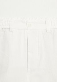 Pantalon en lin blanc avec une taille plate à dos élastique ajustable, une fermeture boutonnée et des poches latérales sans coutures.