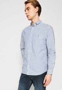 Camisa de cuadros azul y blanca con cuello, mangas largas y un pequeño bolsillo en el pecho. Hecha de una tela ligera con una textura suave.
