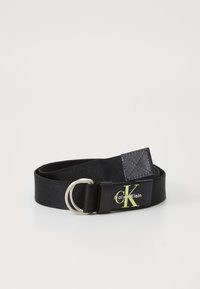 Black fabric belt with a silver metal D-ring buckle. Features a black leather patch with a green logo and white text on one side.