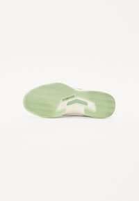 Die Schuhsohle verfügt über ein grünes Gummitraktionsmuster mit einem Fischgrätmuster, einem verstärkten Zehenbereich und einer strukturierten, cremefarbenen Zwischensohle.