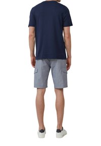 T-shirt di cotone navy, pantaloni cargo grigi a righe con tasche laterali e sneakers bianche con dettagli navy. Abbigliamento casual, vista posteriore.