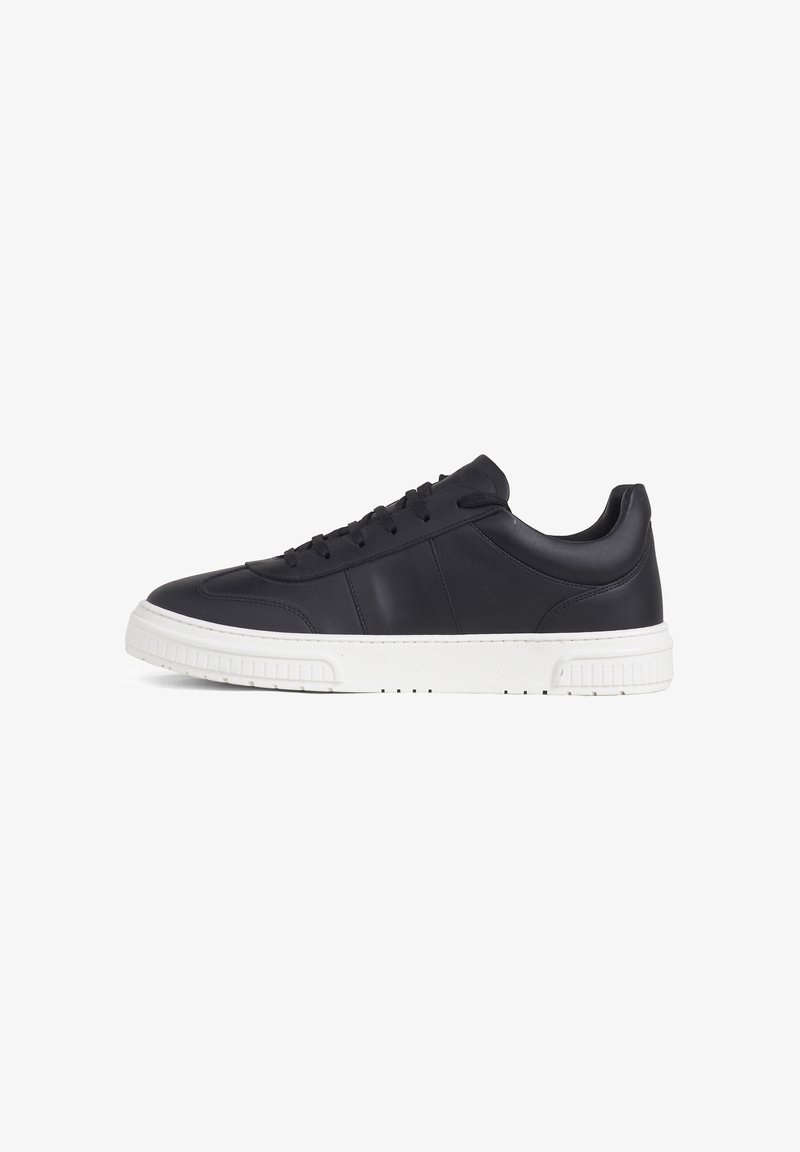 Zwarte lage sneaker met dikke witte zool, veters aan de voorkant en gevoerde kraag, zijaanzicht tegen een witte achtergrond.