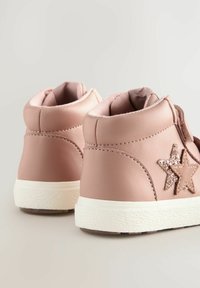 Baskets montantes roses en cuir lisse, avec une semelle en caoutchouc blanche et une étoile scintillante marron sur le côté.