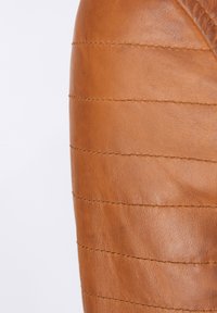 Bruin leren stof met een gladde textuur, voorzien van gestikte horizontale strepen en zichtbare stiksels.