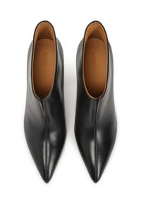 Bottines en cuir noir avec un design à bout pointu, présentant une fermeture éclair discrète à l'avant et une texture lisse et brillante.