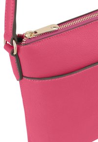 Roze leren crossbody tas met een ritssluiting, voorzien van goudkleurige hardware en een gestructureerd oppervlak. Inclusief een contrasterende zwarte accenten.