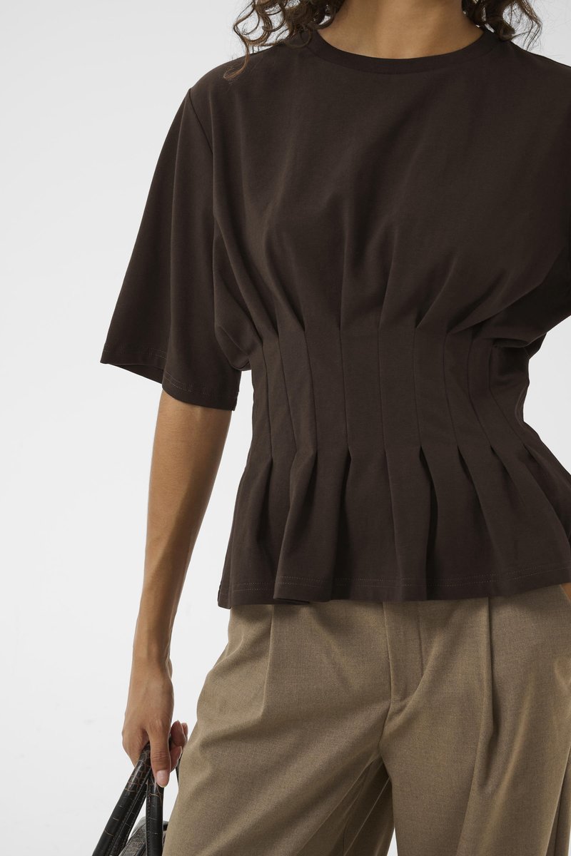 Haut en coton brun à manches courtes avec un détail de taille plissée, associé à un pantalon beige. Design simple, texture lisse et lignes épurées.