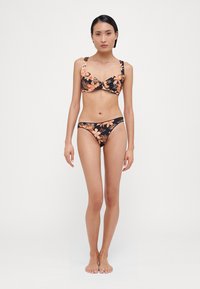 Fekete virágmintás bikini szett narancssárga trópusi virágokkal, puha anyagból, formázott kosarakkal és állítható pántokkal. A bikini alsó része alacsony derekú fazonú.
