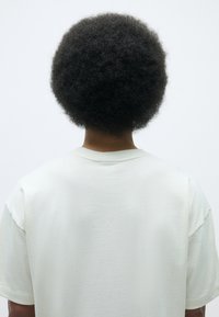 Light-colored, oversized, short-sleeve t-shirt made of soft cotton. Features a round neckline and minimal stitching details.