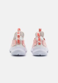 Pink and white athletic shoes with a mesh upper, padded heel, and a textured white sole. Features branded heel tabs and cut-out designs.