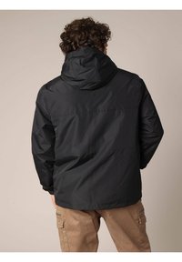 Zwarte hoodiejack gemaakt van gladde stof; heeft een ontspannen pasvorm en twee zijzakken; het achteraanzicht toont een eenvoudig ontwerp zonder logo's.