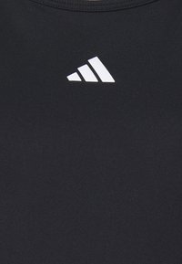 Černé sportovní tričko s hladkou texturou, s bílým logem Adidas ve trojúhelníkovém designu na oblasti hrudníku.