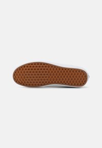 Rubber shoe sole with a textured, honeycomb pattern in brown. White edges contour the sole; flat design for grip and comfort.