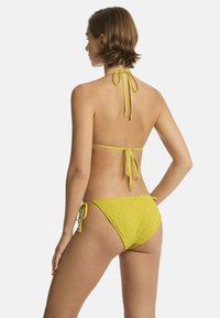 Geel bikini met een gestructureerd ontwerp met bloemenpatronen, halterbandjes en verstelbare zijknoopjes aan de onderkant.