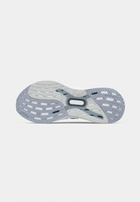 Kenkäpohja, jossa harmaa ja valkoinen värimaailma, ja siinä on uurteinen ja reikäkäs pintakuvio tarjoten pitoa ja joustavuutta.