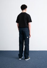 Czarny bawełniany t-shirt o luźnym kroju, połączony z granatowymi spodniami cargo z wieloma kieszeniami i naszywką na nodze.