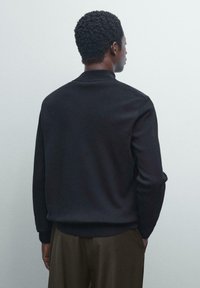 Pullover nero, con texture, colletto, maniche lunghe e polsini e orlo a coste. La parte posteriore presenta un design semplice e pulito.