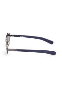 Metallbågar med mörkgrå tonade linser och tempel i marinblå plast med subtilt varumärke på sidan. Lätt och hållbar design.