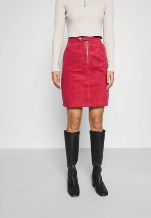 Czerwona mini spódnica sztruksowa z przednim zamkiem błyskawicznym i srebrnym detalem w postaci pierścienia. Zestawiona z kremowym, prążkowanym, długim rękawem oraz czarnymi kozakami za kolano.