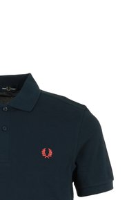 Mörkblå polotröja med texturerad tyg, tre knappar vid kragen och en liten röd logotyp på vänster bröst.