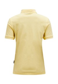 Polo giallo con una texture morbida, colletto classico, maniche corte e un dettaglio con etichetta laterale. Tessuto liscio con un design pulito e semplice.