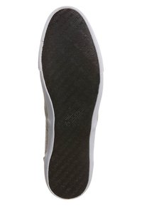 Sole tenisky s texturovanou černou gumou a bílým okrajem. Na povrchu jsou viditelné vytlačené logo.