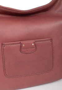 Borsa a tracolla in pelle bordeaux con una texture liscia, dotata di una tasca frontale, accessori in oro e dettagli di cucitura sottili.