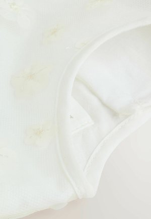 Weißes Kleidungsstück mit floralen Mustern aus einem transparenten Stoff, das weiche Texturen und einen runden Ausschnitt aufweist. Der Rand ist mit einer Naht versehen.