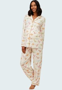 Pyjamaset med krämfärgad tyg och färgglada dinosauriemönster, med pipingdetaljer, långa ärmar och löst sittande byxor.